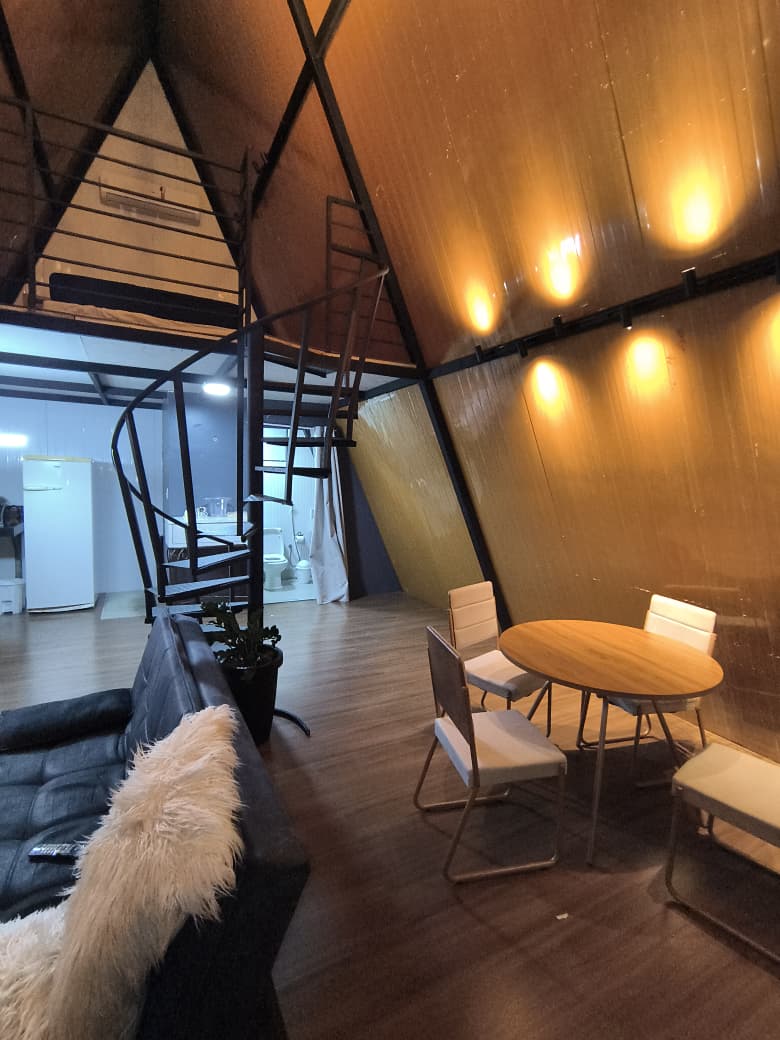 Sala e mesa de jantar com luz quente à noite no chalé Triângulo 60